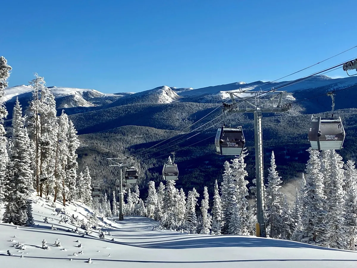 An expansive view of snow-dusted pine trees and a mountain range, with ski lifts in action. Adventurers can be seen skiing, snowboarding, and enjoying the thrill of winter activities amid breathtaking scenery.