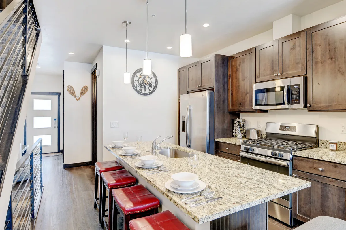 An inviting interior scene highlighting a contemporary chef’s kitchen with a large granite island, sleek bar stools, and stainless steel appliances. The welcoming mood hints at the comforts and quality amenities available inside the villa.